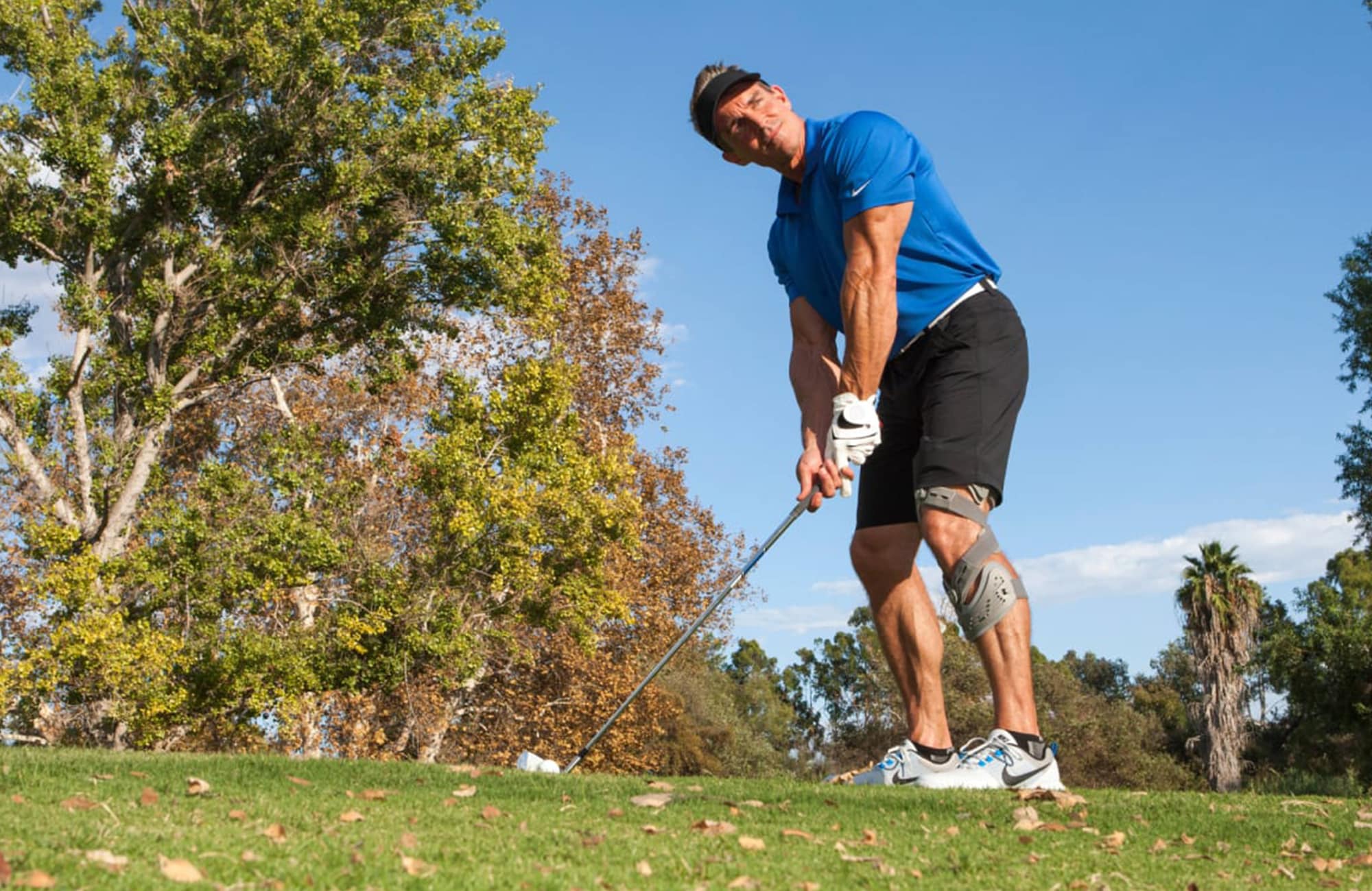 man wearing an orthotic knee brace and playing golf