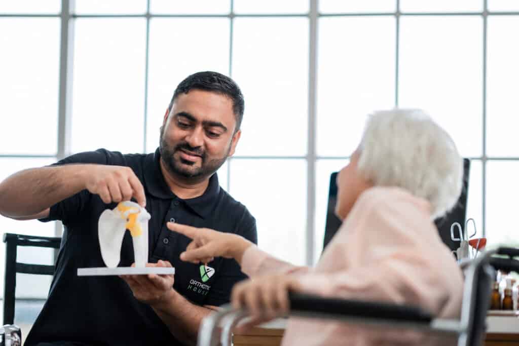 Orthotic House practitioner demonstrating a knee joint model to a patient during a personalised orthotics consultation
